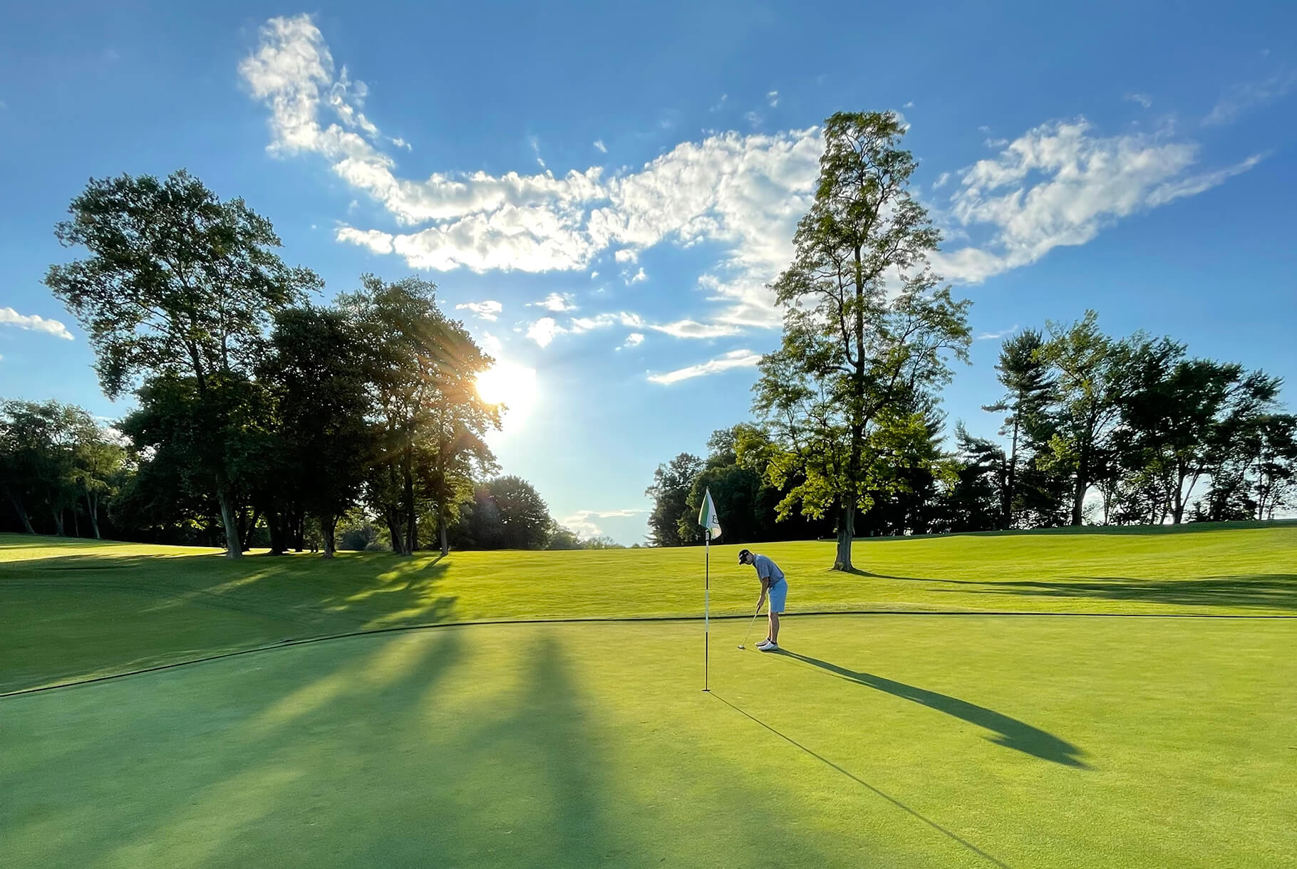 golfer on green under blue sky