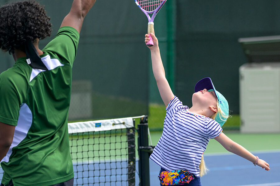 young girl reaching racquet high in the air